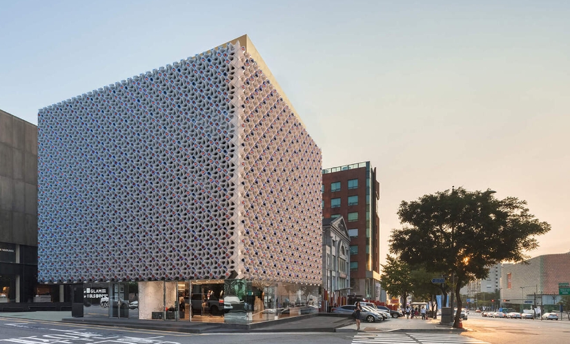 a terra-cotta building facade that offers spaces for bees, birds, and plants