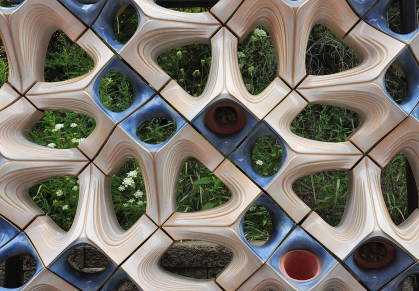 a terra-cotta building facade that offers spaces for bees, birds, and plants